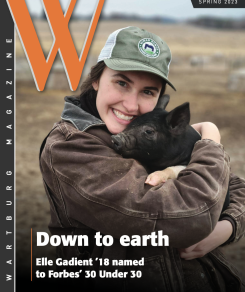 Elle Gadient snuggles a pig on the cover of the Wartburg Alumni Magazine Spring 2023 edition
