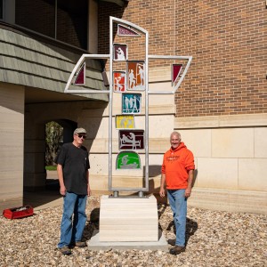 Artist Tom Stancliffe and David Carlson stand beside the Lebenskreuz sculpture.