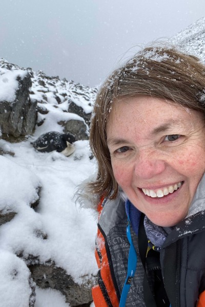 Stacey Snyder takes a a selfie with nesting Adelie penguin.