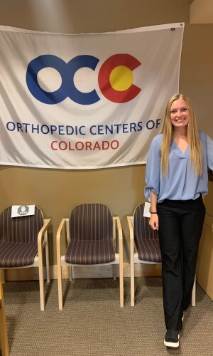 Madison Stoaks in front of a flag that read Orthopedic Centers of Colorado