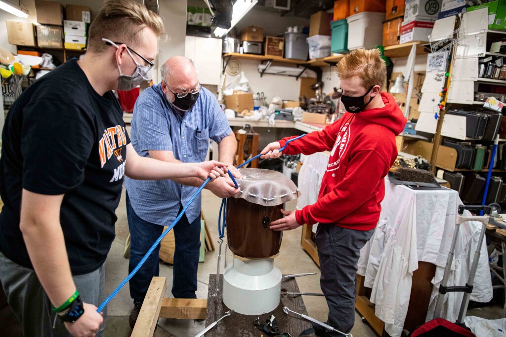 Dr. Craig Hancock (center), Chandler Njus (left) and Ezra Andersen assemble a taiko drum in the Wartburg College instrument repair room.