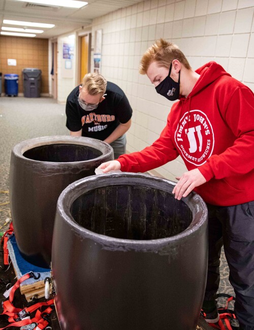Chandler Njus (left) and Ezra Andersen assemble a taiko drum outside the Wartburg College instrument repair room.