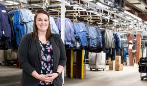 Emily Hauber stands in front of laundered uniforms at CITY Clean and Simple.