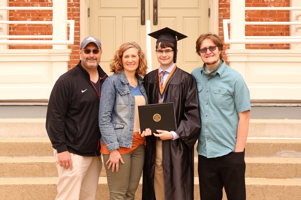 (L to R) Rich, Laurie, Luke ’21, and Adam Everhardt stand in front of Old Main. Luke is in his graduation gown and holding his Wartburg diploma.