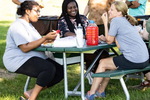 President Neiduski talks with two students during a picnic hosted by Residential Life.
