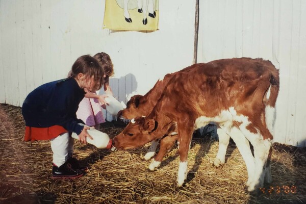 A young Elle Gadient feeds a cow on her family farm.