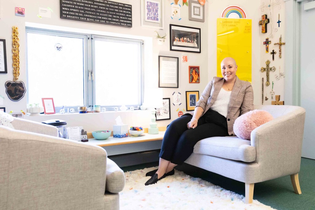 Maggie Falenschek sits on a couch in her office which is brightly decorated with photos, crosses and other artwork.