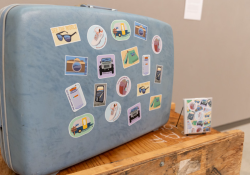 light blue suitcase covered in travel stickers