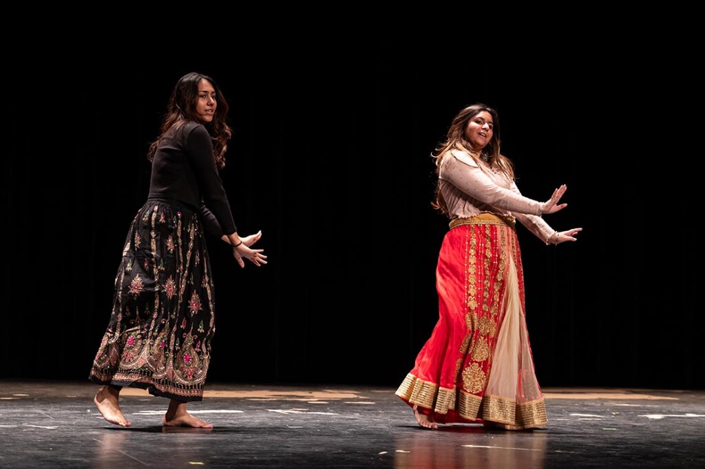 Two women dressed in traditional dresses dance on the Neumann Auditorium stage during the 2024 Culture Show.