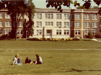 Exterior shot of luther hall with students sitting on the grass.